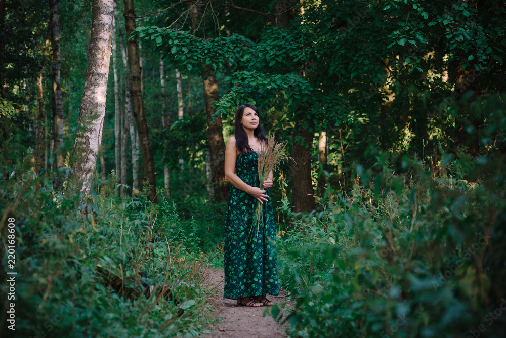 Beautiful woman standing in the woods with a bouquet of spikelets Beautiful woman standing in the woods with a bouquet of spikelets