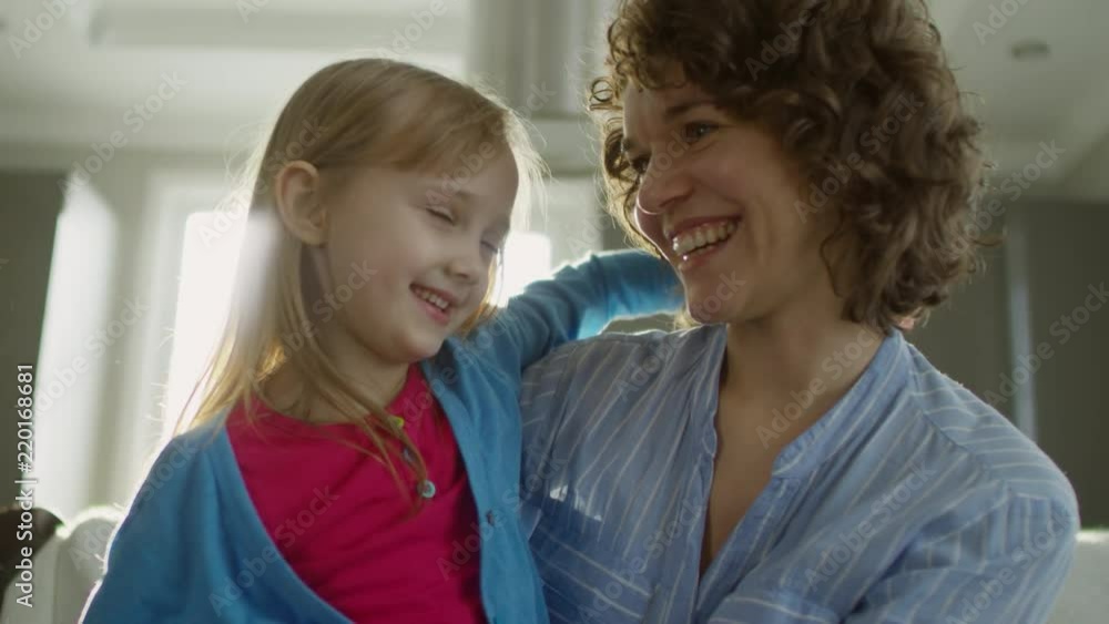 Medium shot of happy mother and daughter sitting on sofa, embracing each other and smiling Medium shot of happy mother and daughter sitting on sofa, embracing each other and smiling