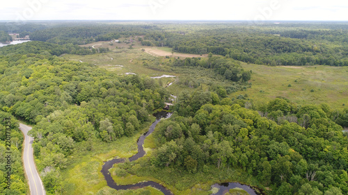 Aerial view of a Long Winding River through the Countryside Farmland passing over a Bridge