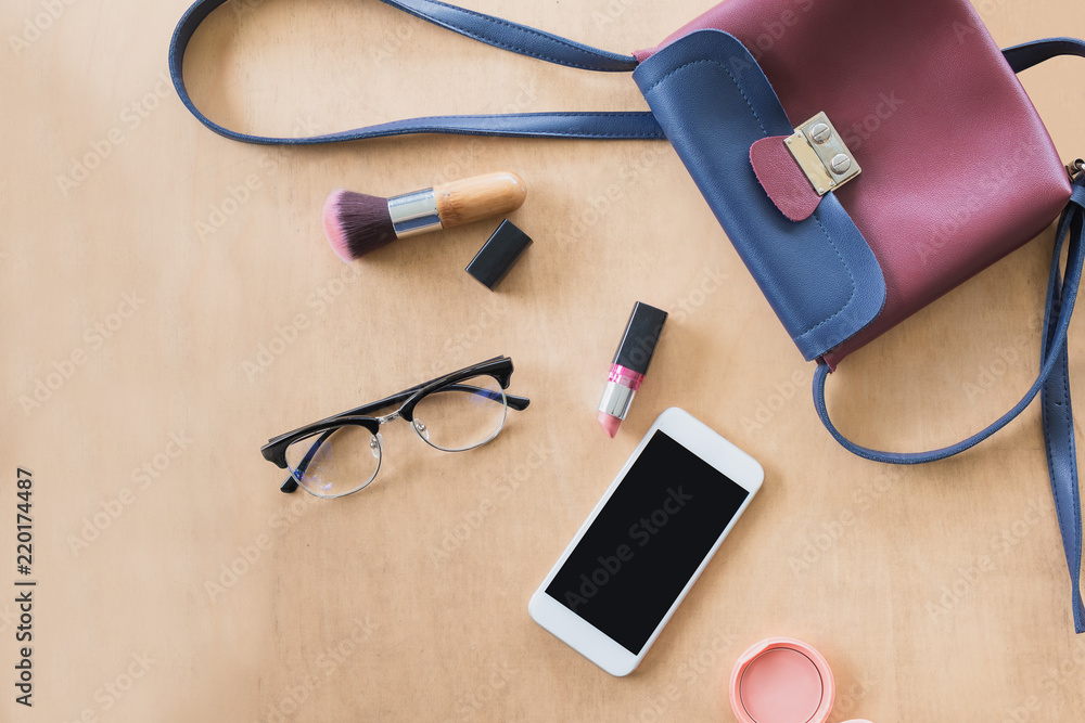 Fashion concept : Flat lay of red leather woman bag open out with cosmetics, accessories and smartphone on wedden background. Fashion concept : Flat lay of red leather woman bag open out with cosmetics, accessories and smartphone on wedden background.