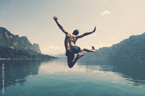 Tela Man jumping with joy by a lake