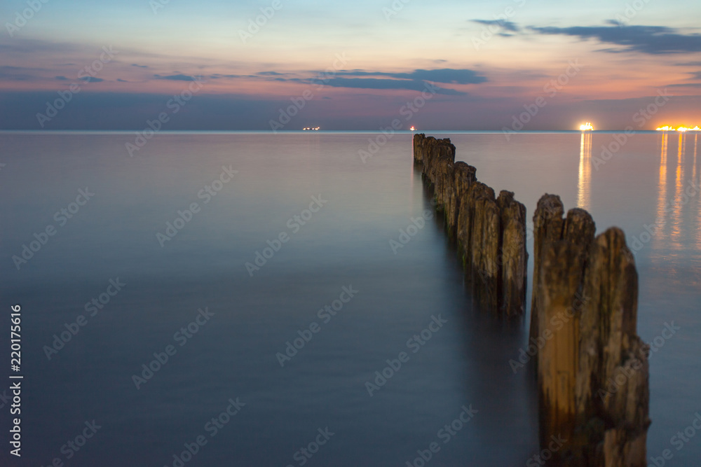 smooth sea surface and breakwaters in twilight on long exposure
