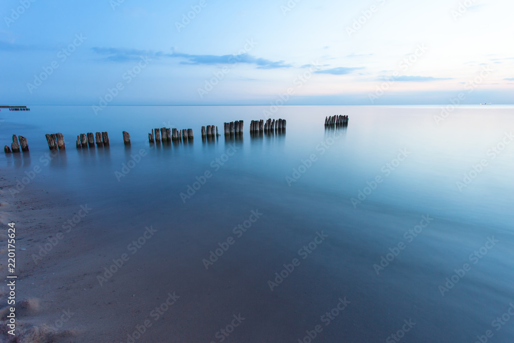 Fototapeta premium smooth sea surface and breakwaters in blue twilight on long exposure