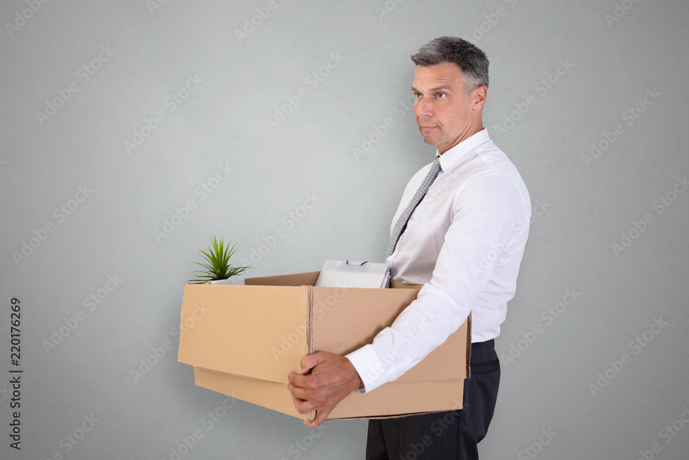 Sad Businessman Carrying Belongings In Cardboard Box Sad Businessman Carrying Belongings In Cardboard Box