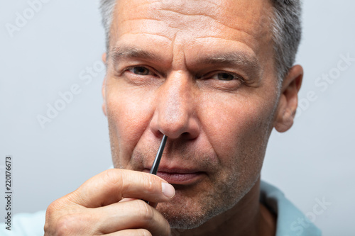 Man Plucking Nose Hair With Tweezers