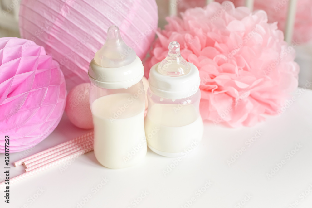 Baby bottles with breast milk with various festive paper decor and balloons in front of baby bedroom. It's a girl or baby birthday celebration concept. Baby shower concept. Baby bottles with breast milk with various festive paper decor and balloons in front of baby bedroom. It's a girl or baby birthday celebration concept. Baby shower concept.