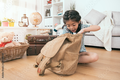Foto kid looking for something in her backpack.
