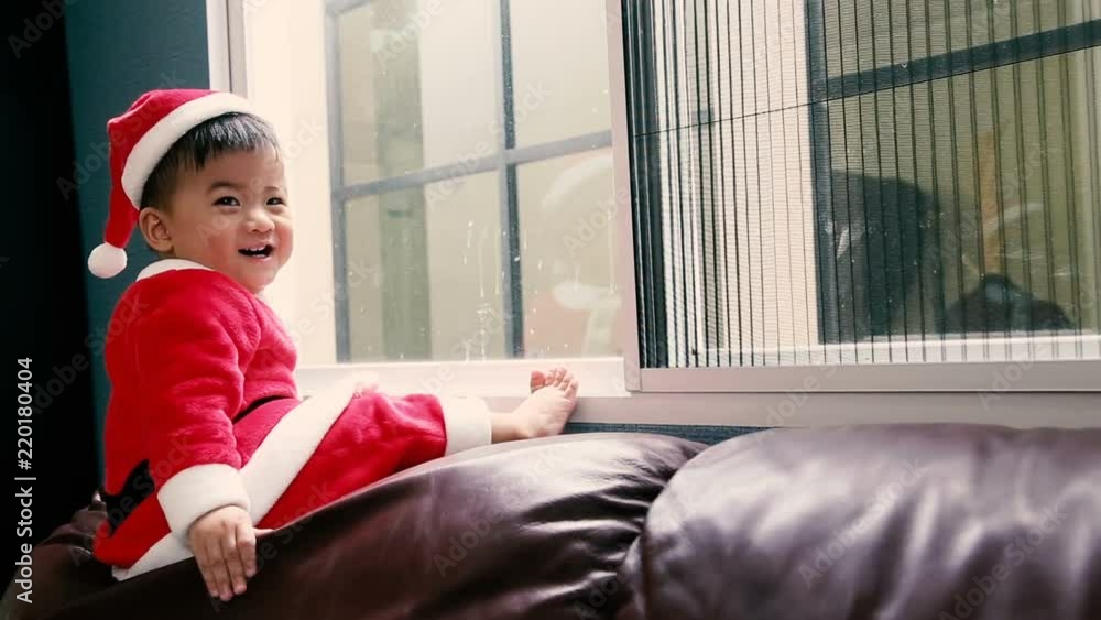 Baby in santa dresses and sitting at the window on christmas day Baby in santa dresses and sitting at the window on christmas day