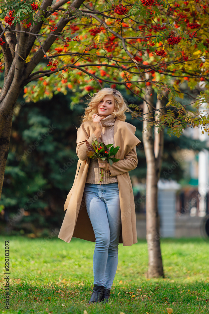 Beautiful elegant woman standing under the rowan tree in autumn park Beautiful elegant woman standing under the rowan tree in autumn park
