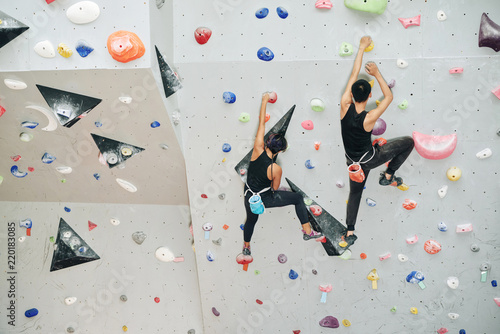 Photography Couple enjoying climbing on artificial wall in gym