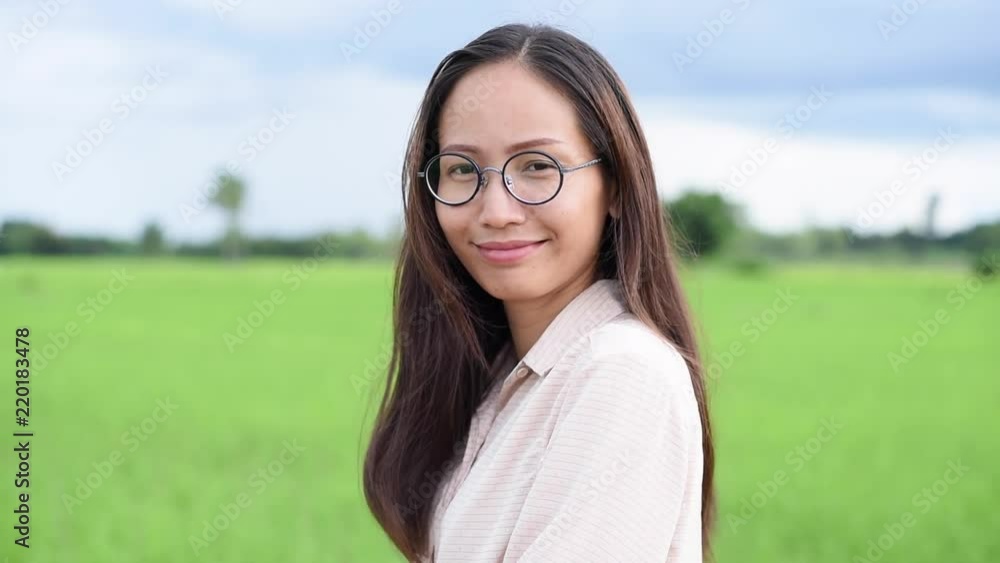 Slow motion. Close up of young woman looking to camera with rice field background Slow motion. Close up of young woman looking to camera with rice field background