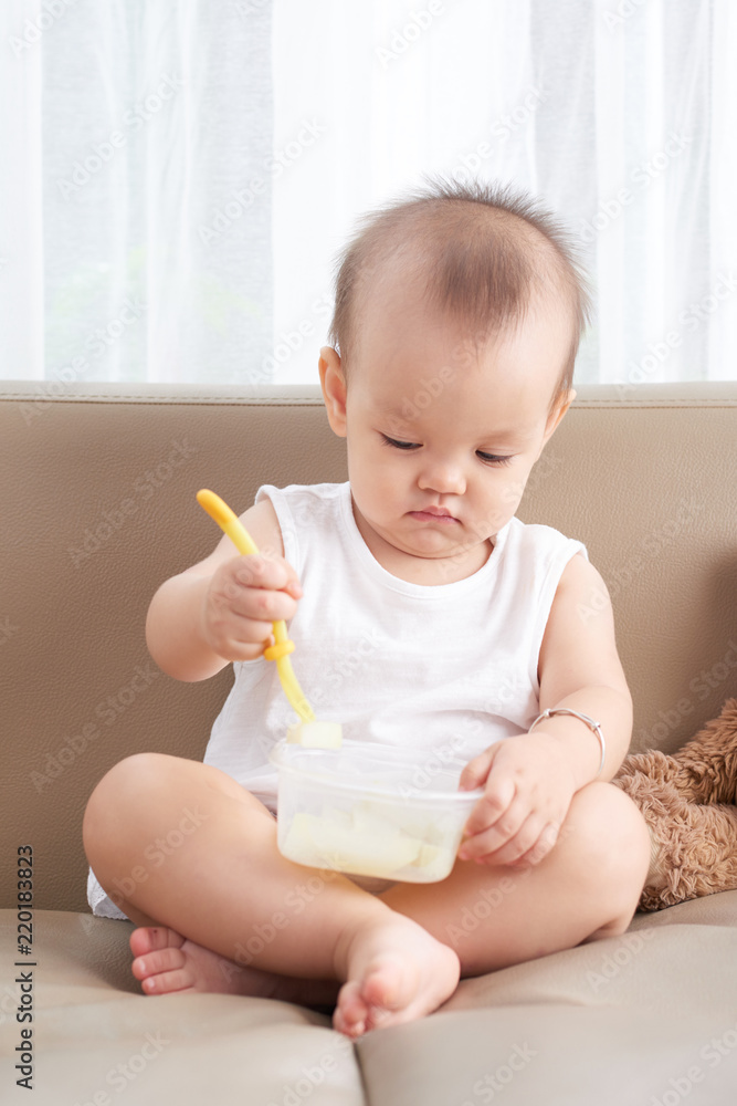 Happy infant baby girl concentrated on eating Happy infant baby girl concentrated on eating