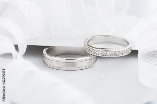 Two silver wedding rings with diamonds on gray background