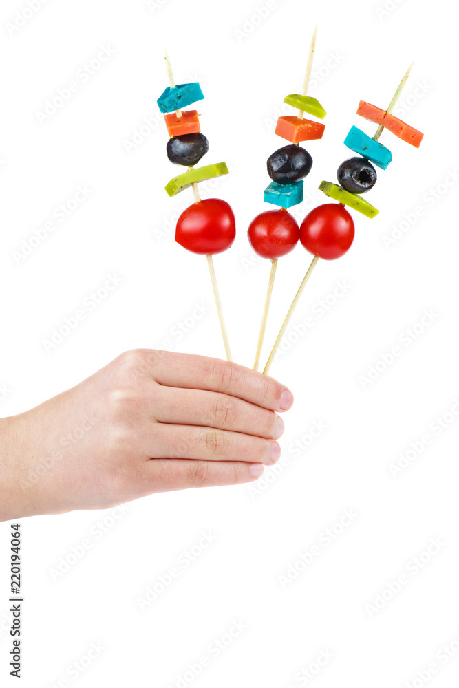 Hand hold three skewers with cheese, tomato and olives Hand hold three skewers with cheese, tomato and olives