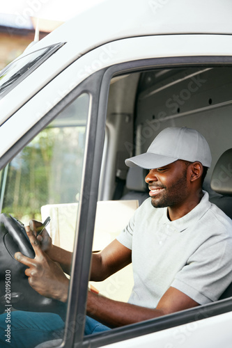 Courier. Delivery Man Reading Addresses Sitting In Delivery Van