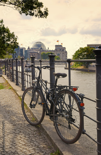 bicycle on the river spree and Reichstag government; in the background in warm evening light, Berlin capital of Germany, Europe, copy space