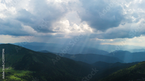 The rays of the sun make their way through the stormy sky in the mountains