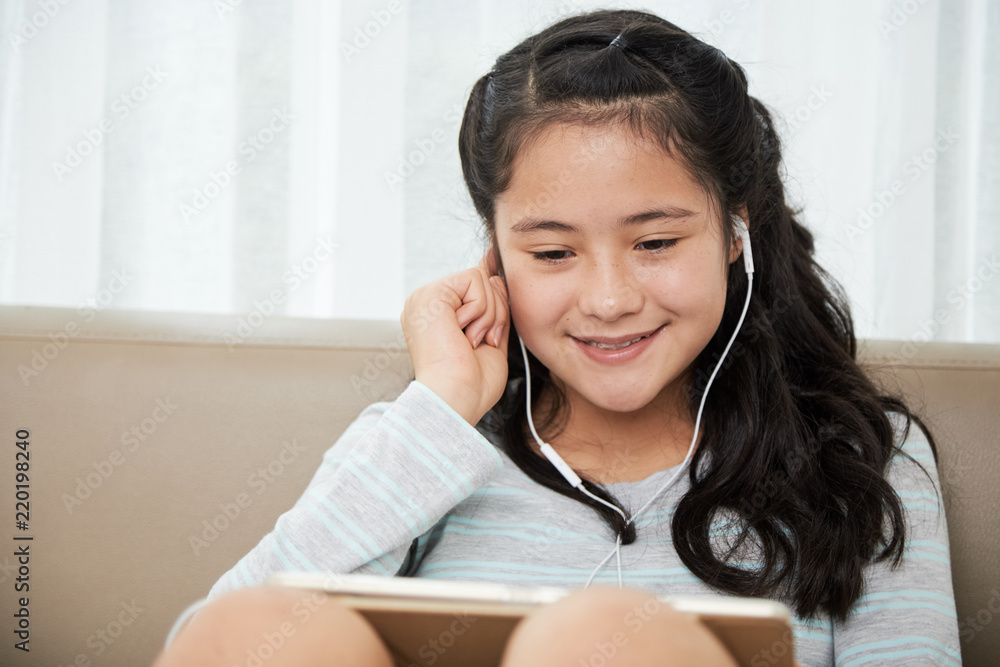 Smiling pretty girl watching videos or playing games on tablet computer Smiling pretty girl watching videos or playing games on tablet computer