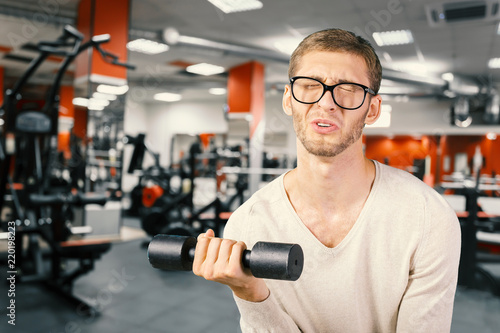 Slika na platnu Funny weak man tries to lift a weight