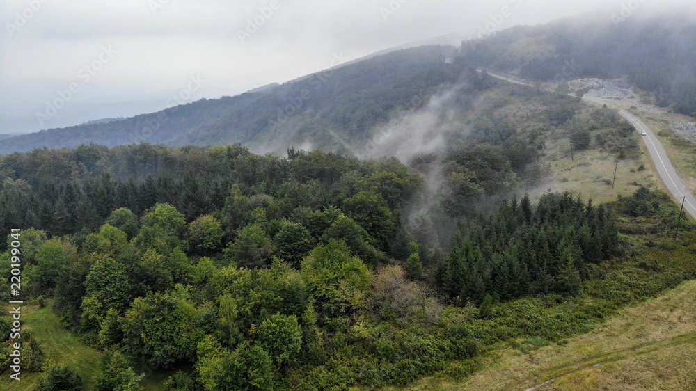 Aerial view of mountain road in the fog. First signs of autumn, yellow ends on leaves. Aerial view of mountain road in the fog. First signs of autumn, yellow ends on leaves.