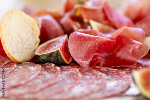Light Italian snacks. A buffet table at a dinner party. Food tray with delicious salami, pieces of sliced ham, sausage. Cutting sausage and cured meat on a celebratory table.