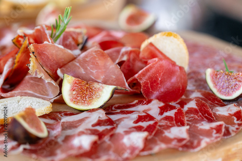 Light Italian snacks. A buffet table at a dinner party. Food tray with delicious salami, pieces of sliced ham, sausage. Cutting sausage and cured meat on a celebratory table.