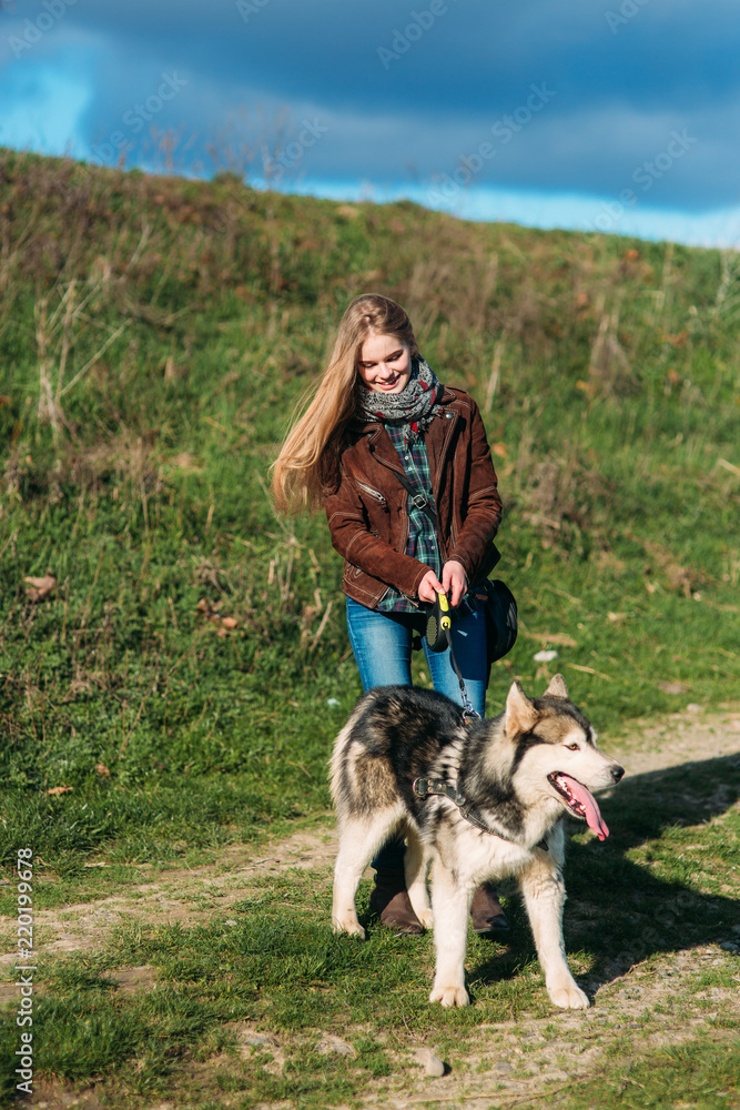 A girl is walking with a dog along the embankment. Beautiful husky dog