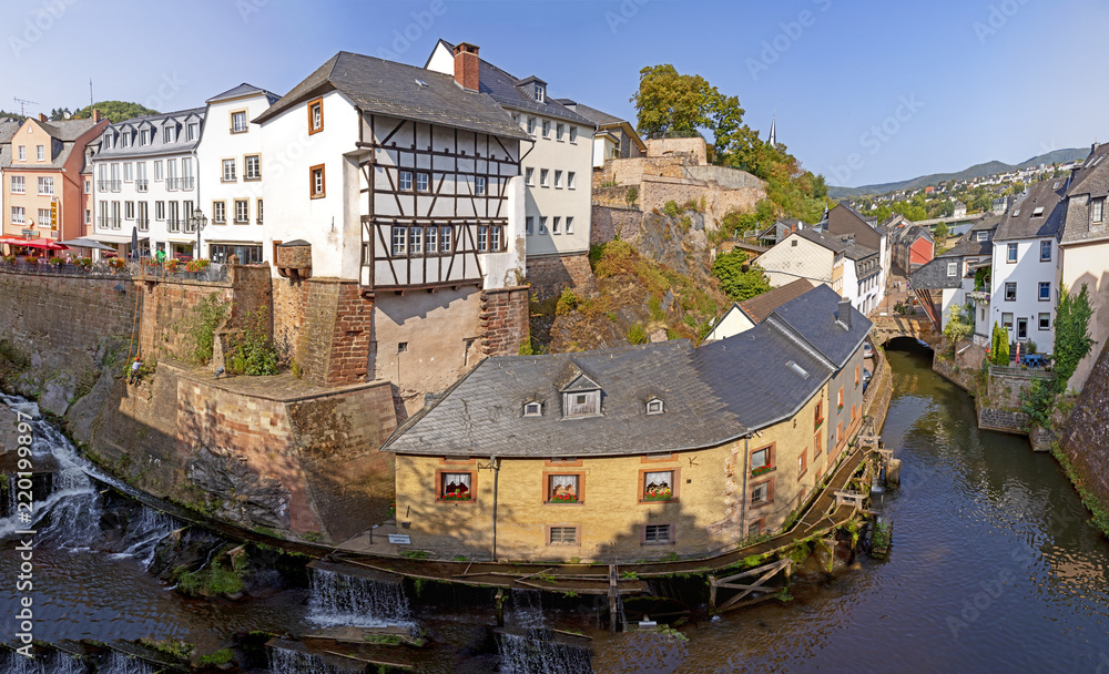 Obraz premium waterfall in the city center of Saarburg, Germany surrounded by houses on a hill