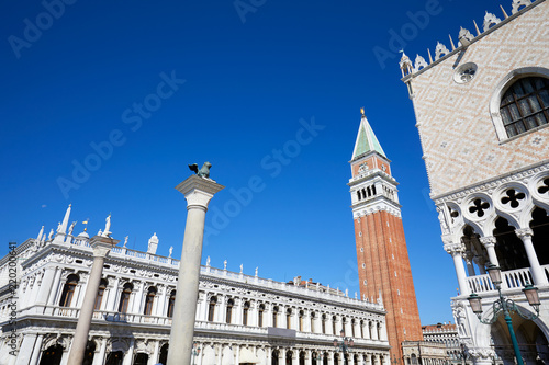 San Marco bell tower, lion statue and Doge palace wide angle view, clear blue sky in Venice, Italy