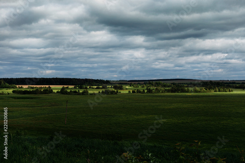 Landscape with a field  a hills and dark clouds. 