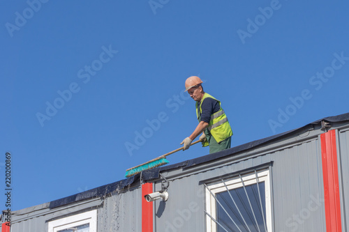 Wallpaper Mural Worker at the construction site cleans the roof of the water with a brush Torontodigital.ca