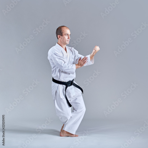 A man in a low rack coaches a formal karate exercise