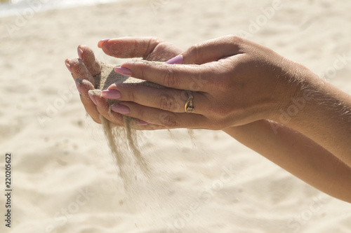 The sand is pouring from woman's hands.