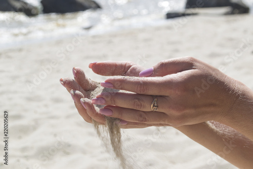 The sand is pouring from woman's hands.