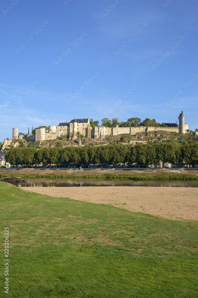 Chinon chateau stands on the hill in early autumn morning sunshine high above the River Vienne, Indre-et-Loire, France. The river has much less water at the end of summer.