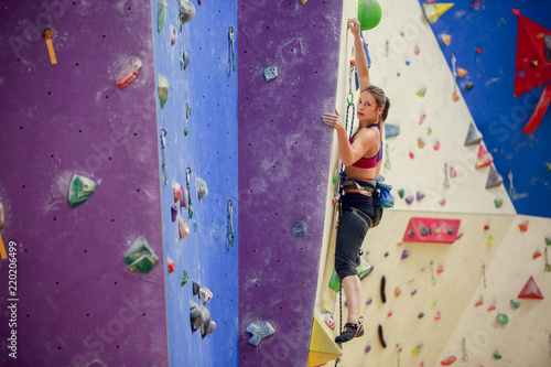 Photo of young athlete in training on purple wall for rock climbing
