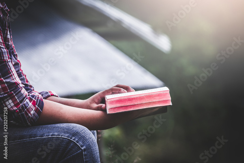Close up hands of male holding and reading Bible on mountain in morning