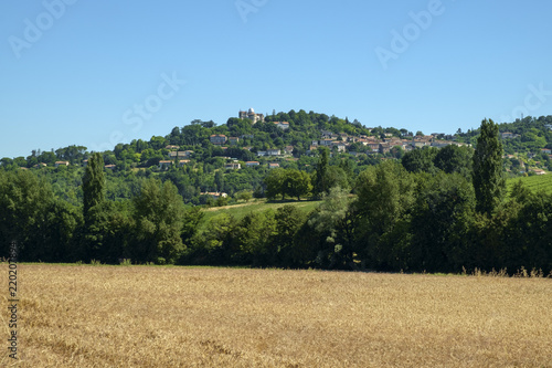 Canvas Print Looking across summer fields towards hilltop Penne d'Agenais and its Notre Dame de Peyragude basilica with its silver dome in rural Lot et Garonne, France
