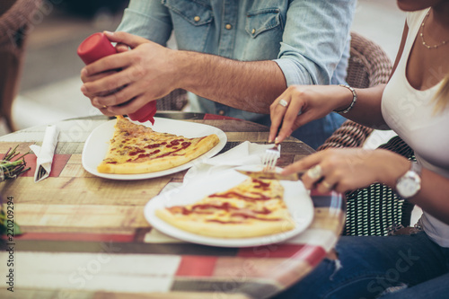 Couple eating pizza snack outdoors, close up.They are sharing pizza and eating.