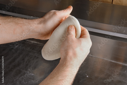 Hands of Chef preparing dough for italian pizza