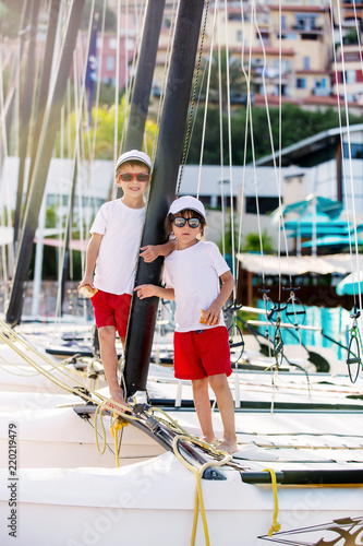 Two beautiful children, boy brothers, standing on a boat, smiling