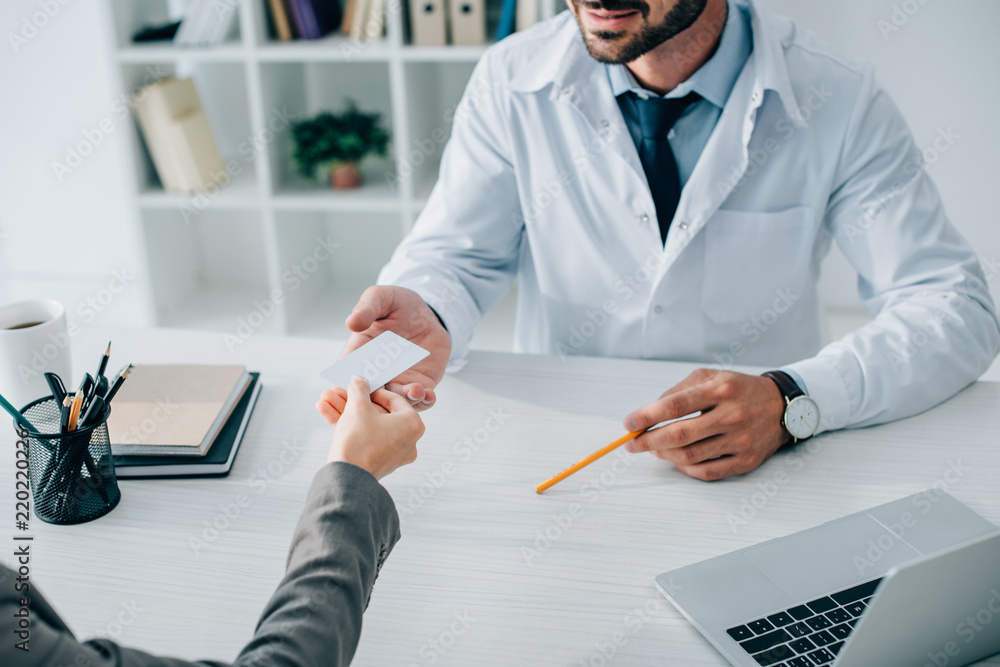 Φωτογραφία cropped image of patient giving business card to doctor in clinic
