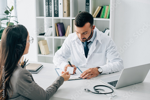 Fotografie patient giving id card to general practitioner to fill insurance claim form in c