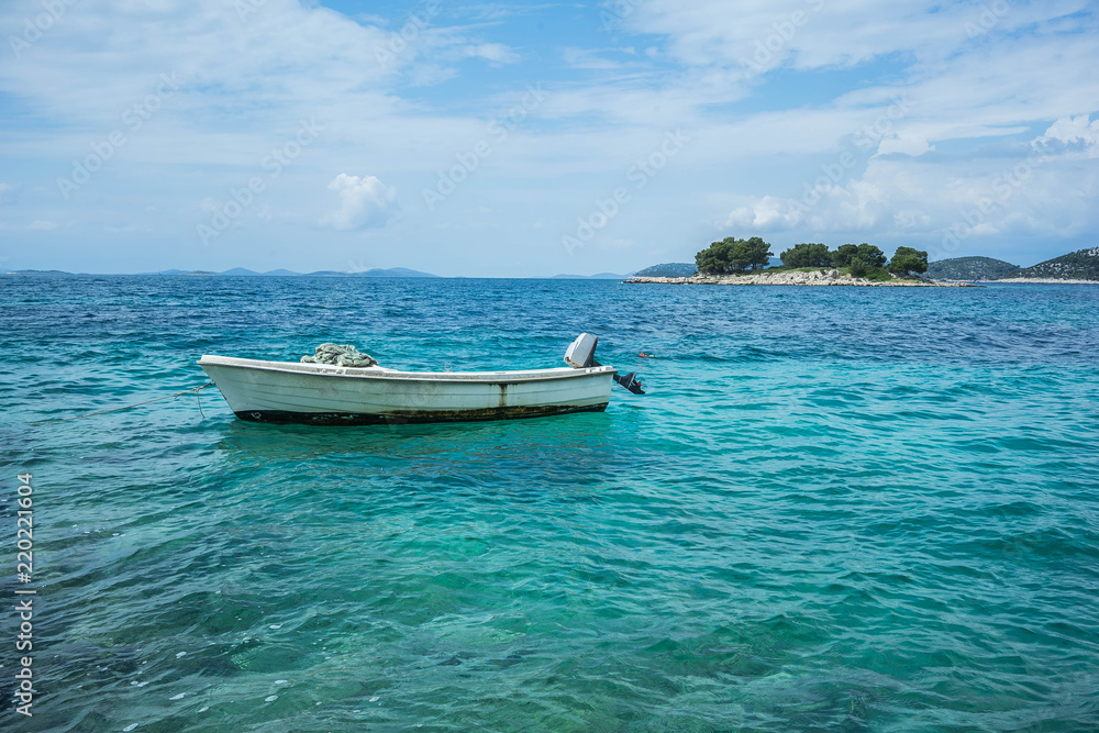 Naklejka premium Small boat floating on turquoise Adriatic Sea near Croatian island