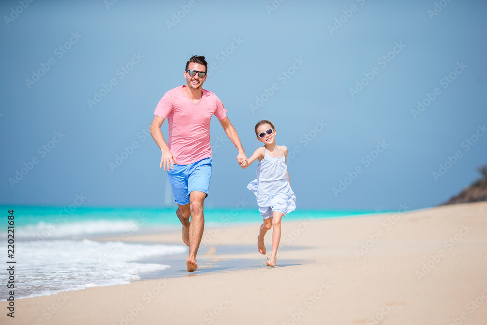 Family of father and sporty little girl having fun on the beach Family of father and sporty little girl having fun on the beach
