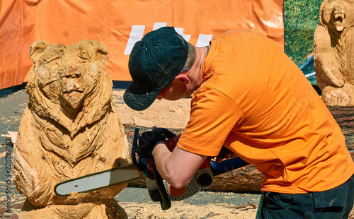 Bild auf Leinwand Experienced carpenter making a big wooden bear sculpture with a chainsaw
