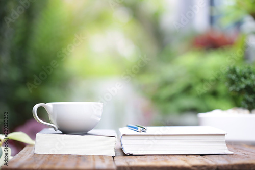 White coffee cup with notebooks on wooden table at outdoor