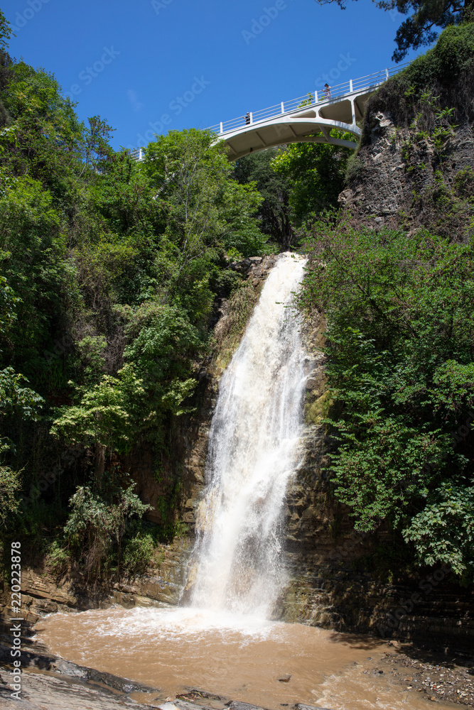 high waterfall and observation deck a bridge in the botanical garden of Tbilisi