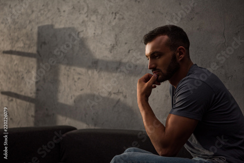 lonely pensive man sitting on sofa at home