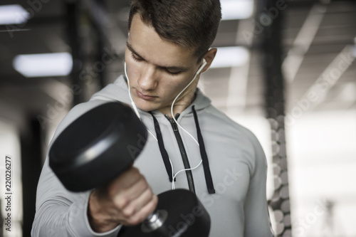 Muscular bodybuilder guy doing exercises with dumbbells in gym © Maksym